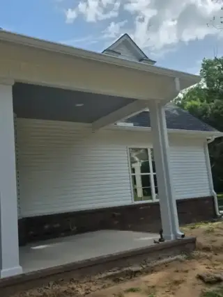 Newly constructed White Hall home displaying professional seamless gutter installation along the roofline and covered porch area.