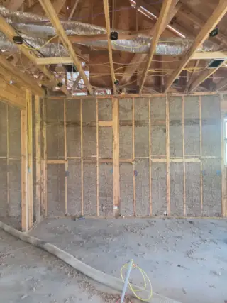 Interior wall framing with blown-in insulation installed between studs during new construction in White Hall, Arkansas